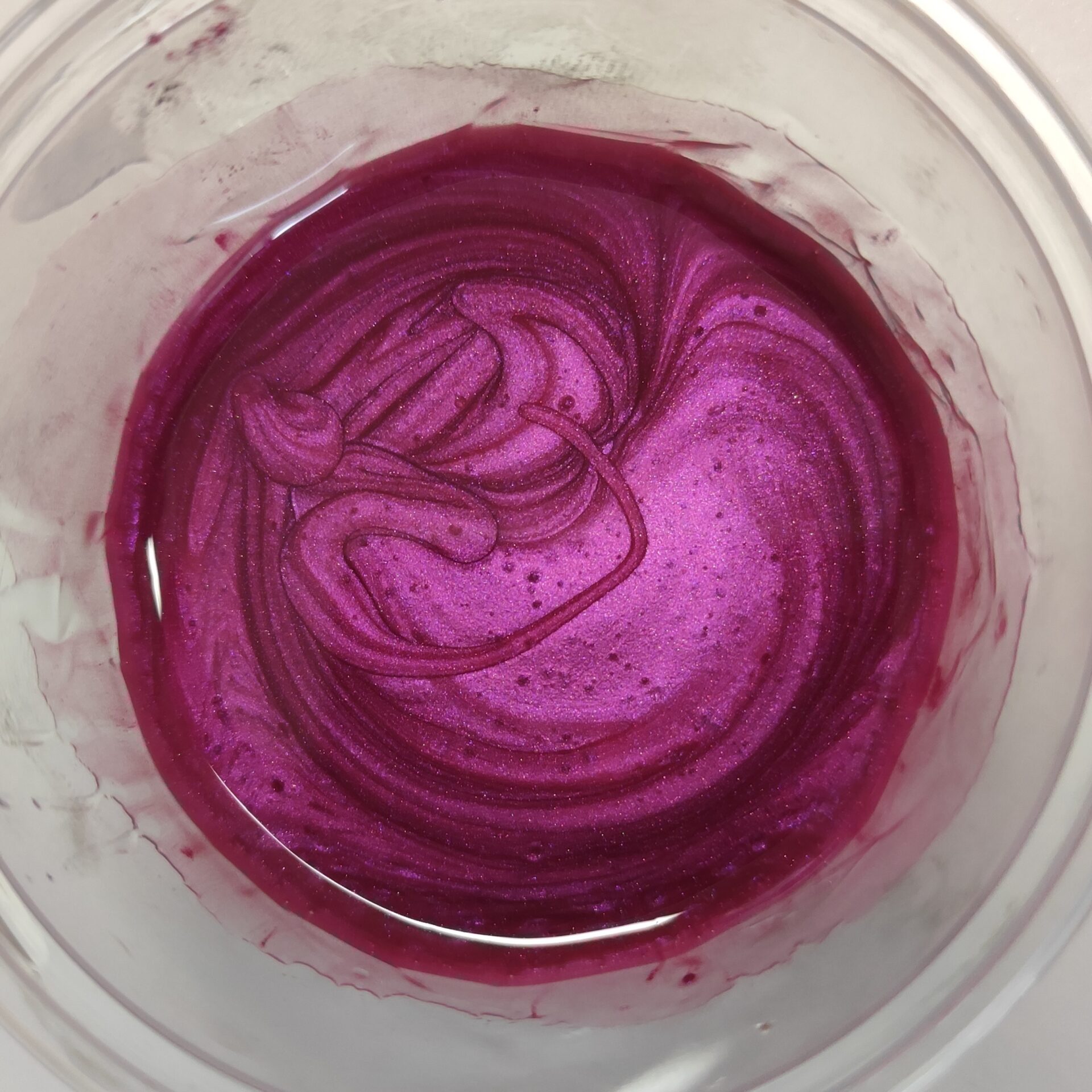 Różowy pigment wymieszany z żywicą w przezroczystym pojemniku